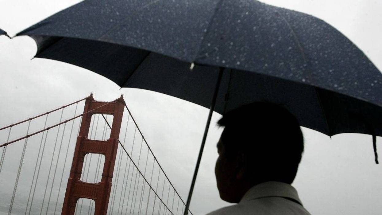 A man holds an umbrella as he views the north tower of the Golden Gate Bridge April 12, 2006 in Sausalito, California.