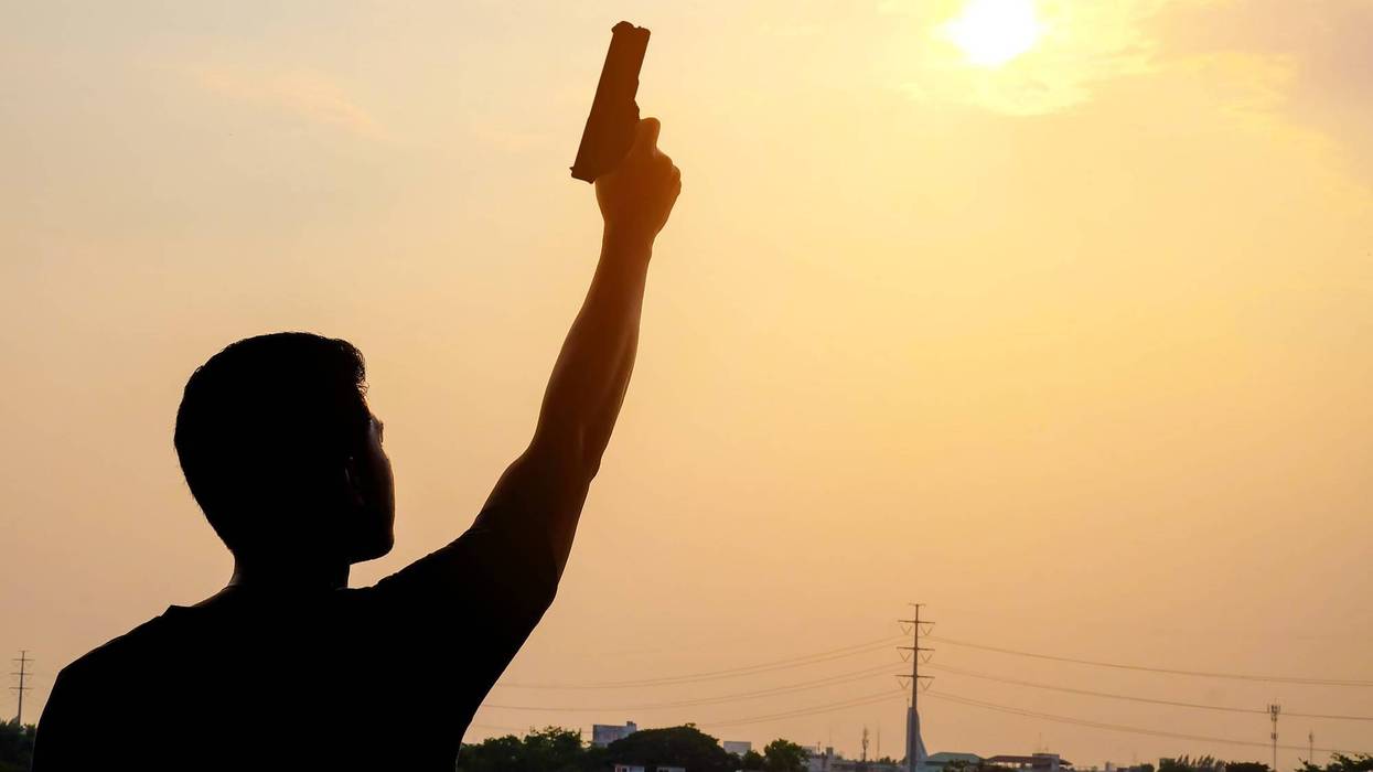 a man lifting a hand holding a gun