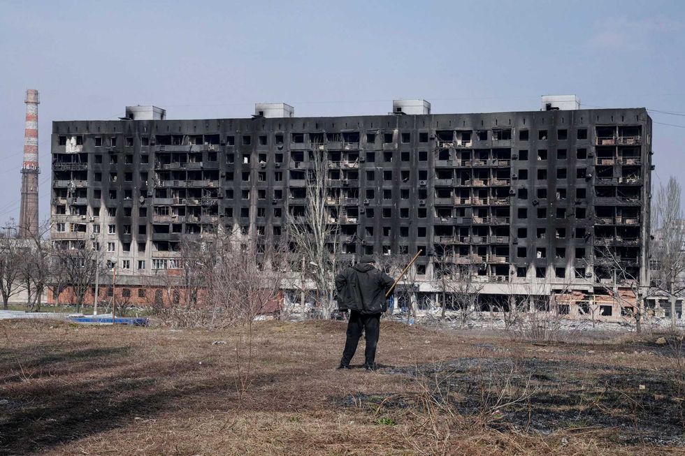 A man looks at a burned apartment building that was damaged by shelling in Mariupol, Ukraine, Sunday, March 13, 2022