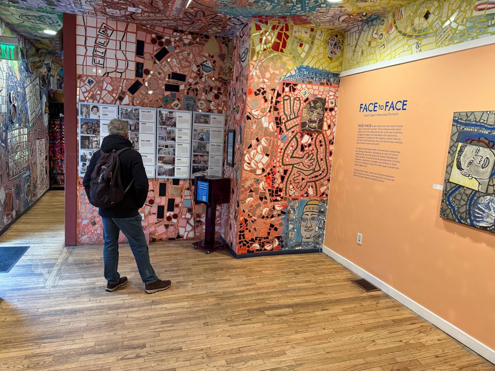 A man peruses the Face To Face exhibit at The Magic Gardens.