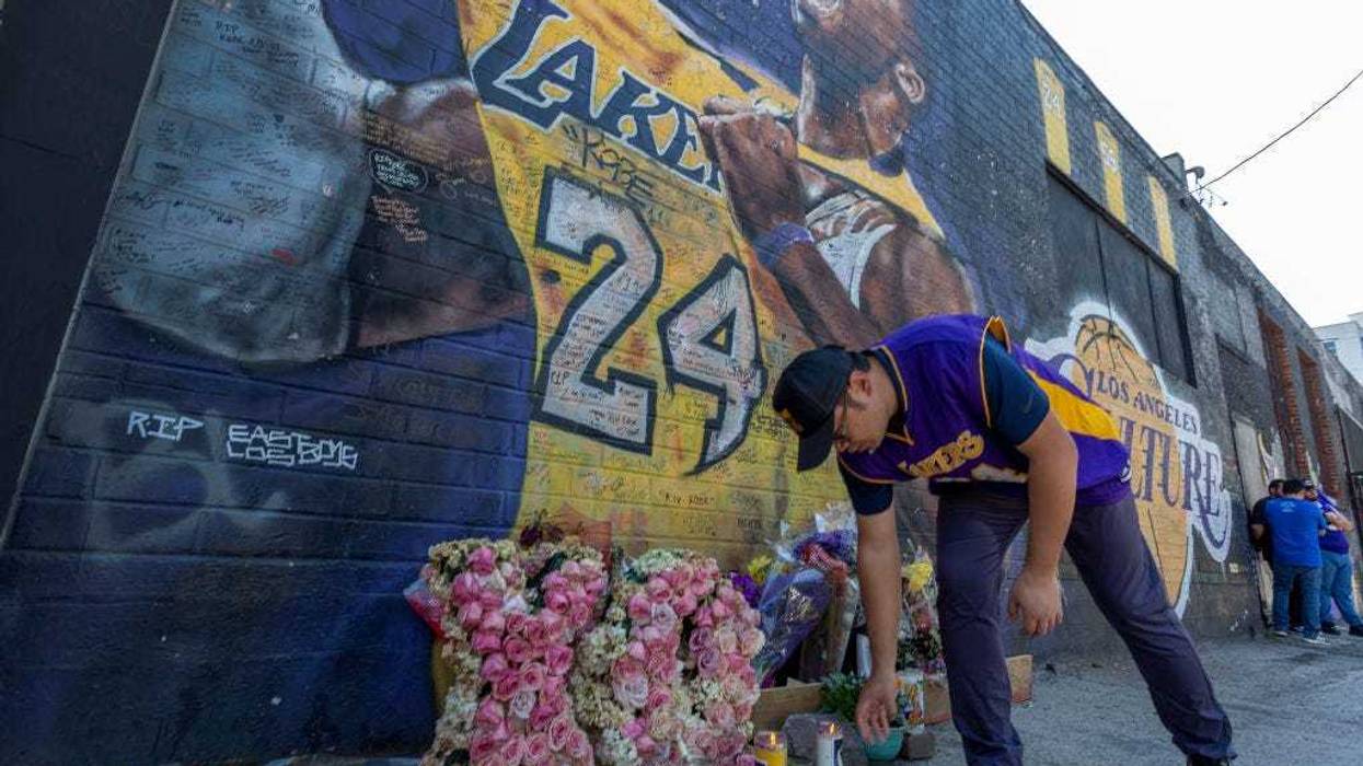A man places a candle near a mural for former Los Angeles Lakers basketball star Kobe Bryant during the official memorial ceremony for him and his daughter, Gianna.