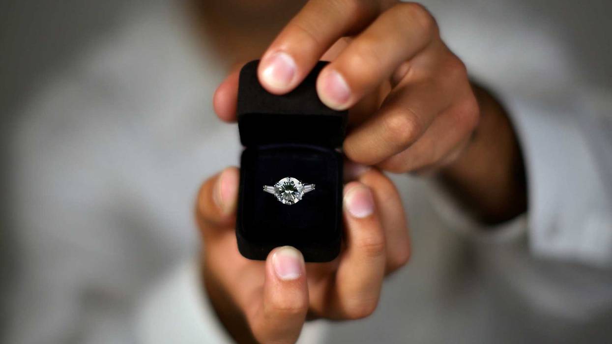 A man proposing and holding up an engagement ring