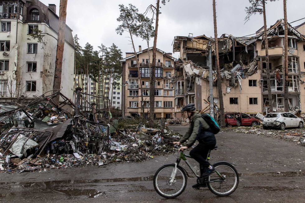 A man rides his bike past destroyed buildings on March 03, 2022 in Irpin, Ukraine. Russia continues assault on Ukraine