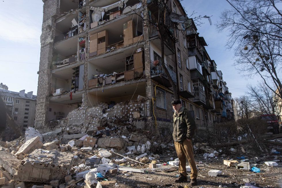 A man stands amid debris in front of a residential apartment complex that was heavily damaged by a Russian attack on March 18, 2022 in Kyiv, Ukraine
