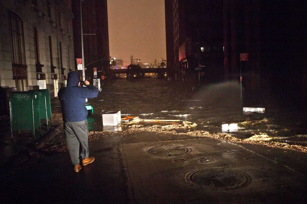 A man takes a photo as floodwaters inundate the Financial District on Oct. 29, 2012