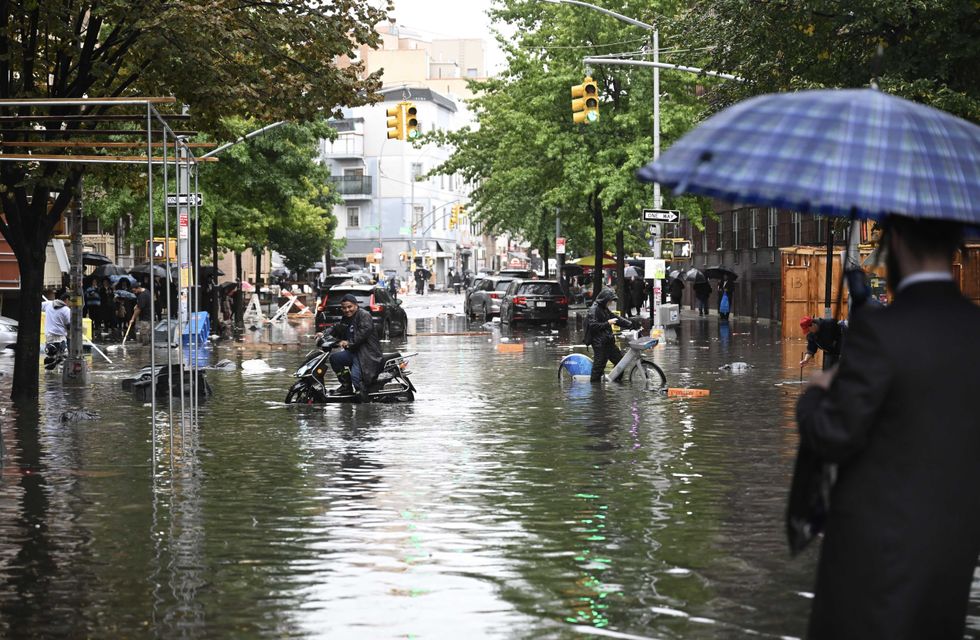 A man tries to pass a flooded street with his bicycle after a heavy rain in Williamsburg, Brooklyn, on September 29, 2023