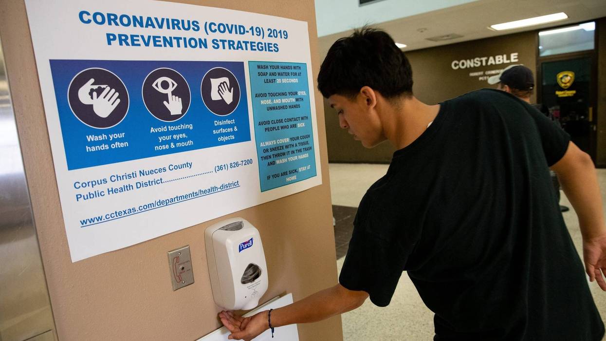 A man uses hand sanitizer underneath a coronavirus prevention sign at the entrance of the Nueces County Courthouse on Friday, March 13, 2020. Covid 19 Corpus 6