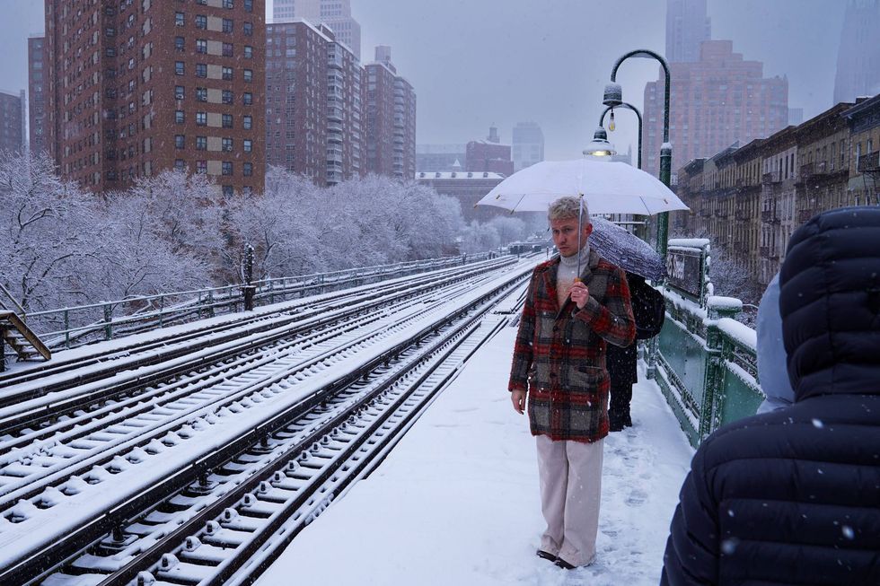 A man waits for a train during a snowstorm in December