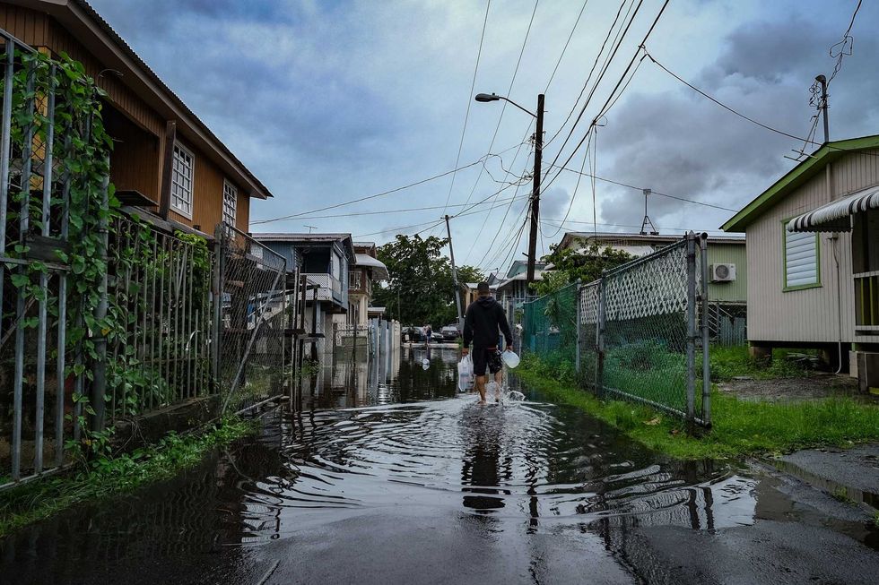 A man walks down a flooded street in the Juana Matos neighborhood of Catano, Puerto Rico, on September 19, 2022, after the passage of Hurricane Fiona.