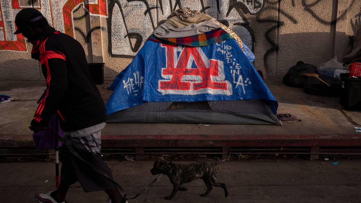 A man walks past a homeless encampment in downtown Los Angeles, Wednesday, Oct. 25, 2023.