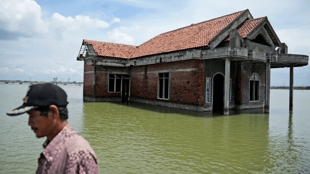 A man walks past a house abandoned after it was inundated by water due to the rising sea level in Sidogemah, Central Java, Indonesia, Nov. 8, 2021. Climate hazards such as flooding, heat waves and drought have worsened more than half of the hundreds of known infectious diseases in people, such as malaria, hantavirus, cholera and even anthrax, according to a new study released Monday, Aug. 8, 2022.