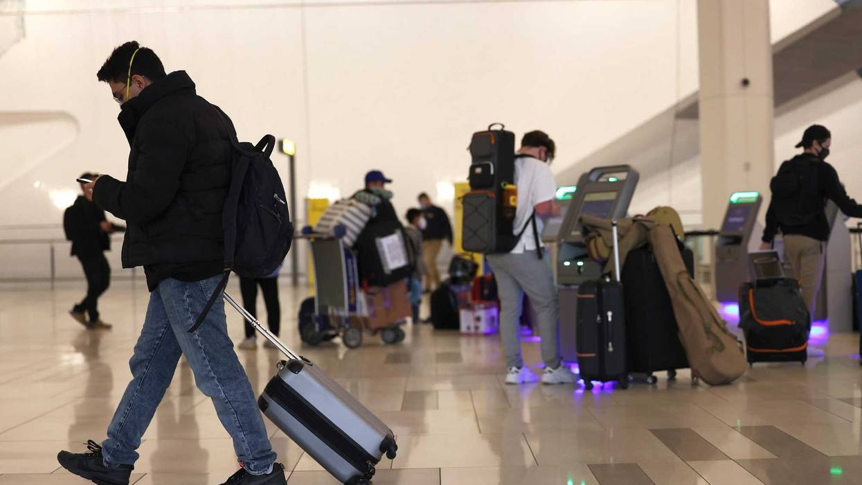 A man walks past people using kiosks to check in for their flights at LaGuardia Airport on November 25, 2020 in Queens.