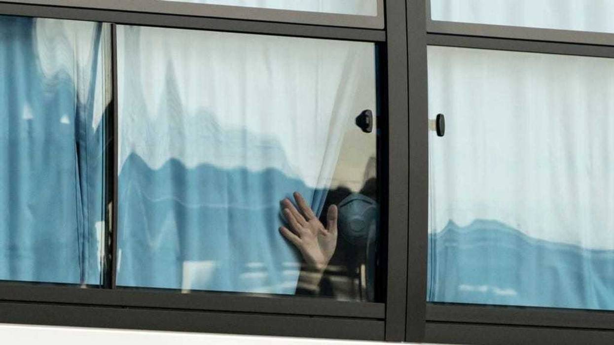 A man waves from a bus carrying passengers who disembarked the quarantined Diamond Princess cruise ship as he leaves the Daikoku Pier on February 19, 2020 in Yokohama, Japan.