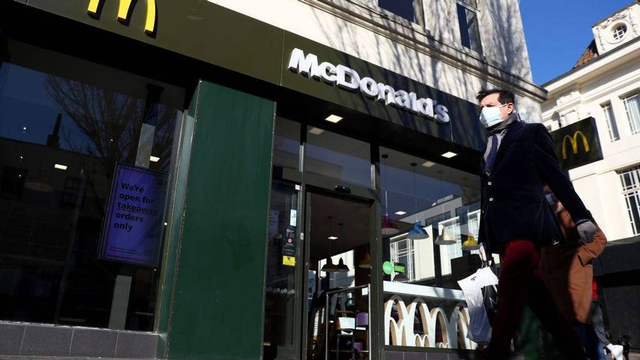 A man wearing a facemask walks past a McDonald's restaurant