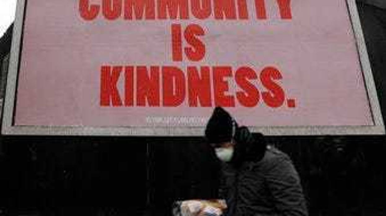 A man wearing a mask to help stop the spread of the coronavirus passes advertising display. (AP Photo/Kirsty Wigglesworth)