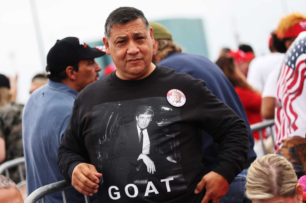 A man wears a "Greatest of All Time" shirt featuring Trump