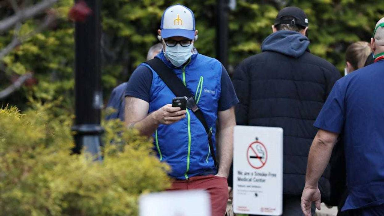A man wears a protective mask while looking at his cell phone during the COVID-19 pandemic on April 21, 2020 in New York City.