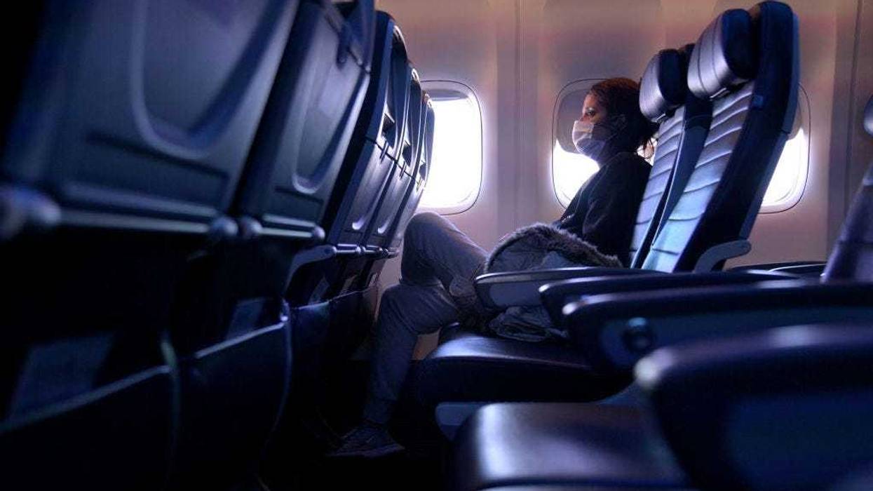 A masked passenger is seen seated on a flight from San Francisco, California to Newark, New Jersey on October 27, 2020. Although virus dissemination on flights is low when people are able to be socially distant, the extremely hard hit airline industry is having to consolidate flights, furthering complicating the dilemma. (Photo by Michael Loccisano/Getty Images)