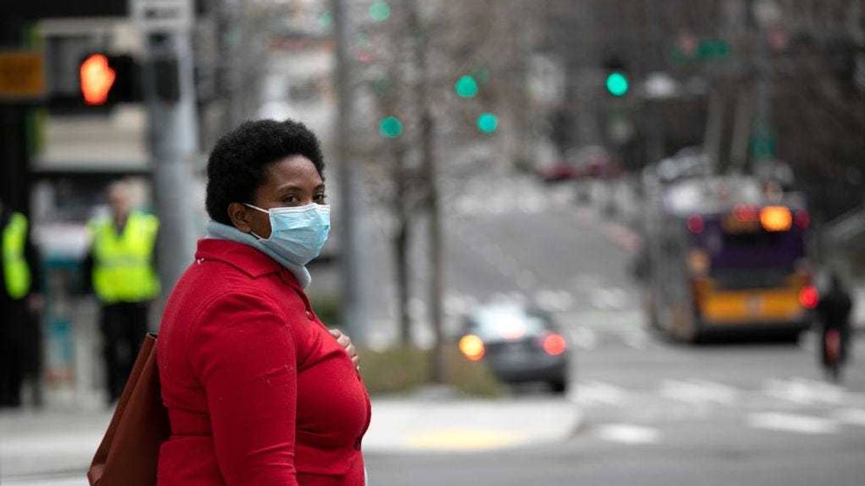 A masked pedestrian pauses near the Amazon headquarters on March 10, 2020 in downtown Seattle, Washington.
