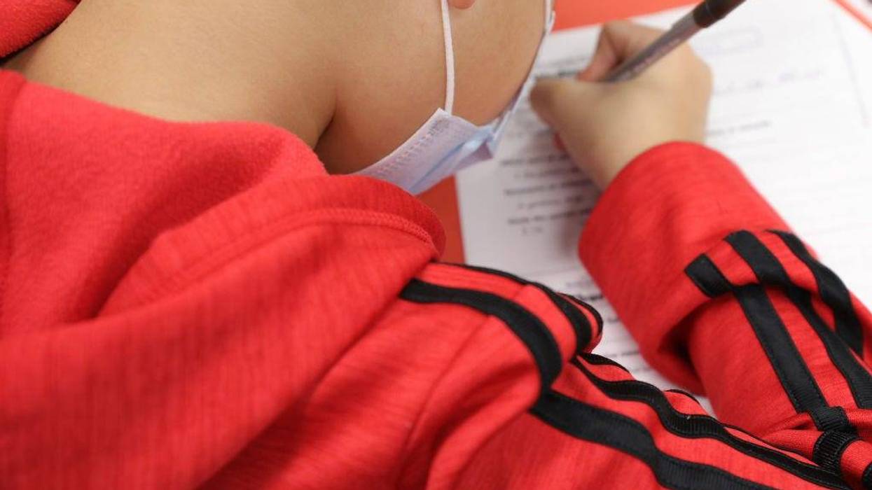A masked student doing work at school