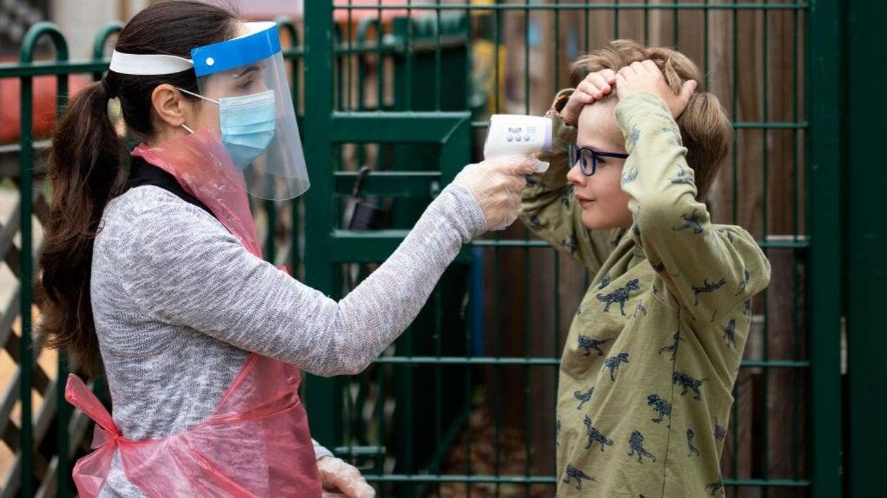A member of staff wearing personal protective equipment (PPE) takes a child's temperature at the Harris Academy's Shortland's school on June 04, 2020 in London, England.