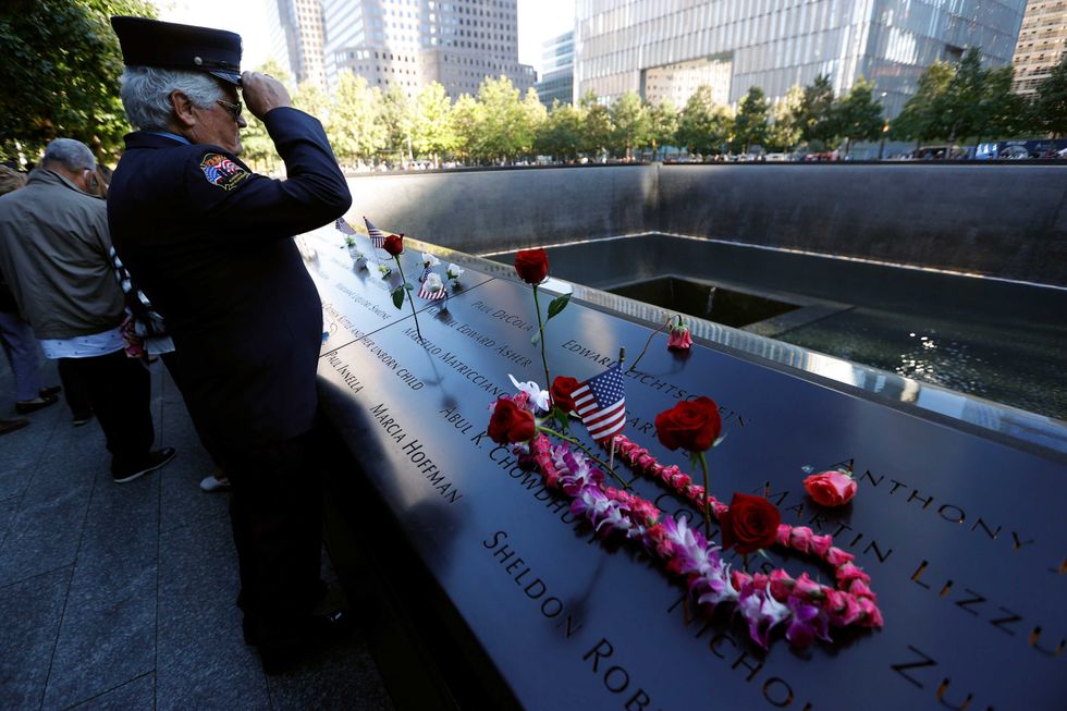 A member of the FDNY visits the reflecting pool during a ceremony at the National September 11 Memorial & Museum commemorating the 20th anniversary of the September 11th terrorist attacks on the World Trade Center on September 11, 2021 in New York City