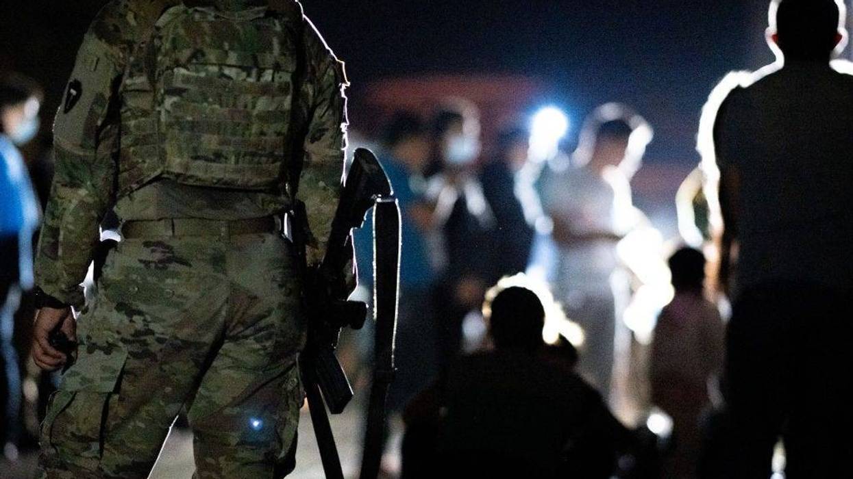 A member of the National Guard stand watch while immigrants wait to be processed after crossing the Rio Grande into the U.S. on June 16, 2021 in Roma, Texas.