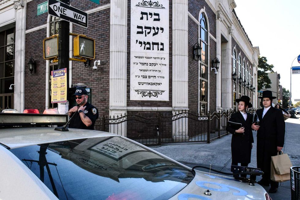 A member of the NYPD patrols in front of the synagogue Congregation Bais Yaakov Nechamia Dsatmar on Oct. 13, 2023 in Williamsburg