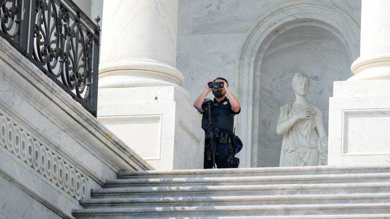 A member of the U.S. Capitol Police uses binoculars at his post on the East Front of the building.
