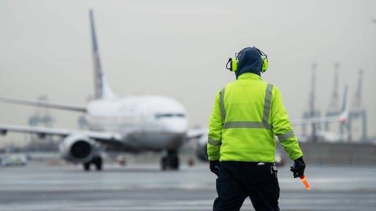 A member of the United ground crew directs a plane to the gate at Terminal A