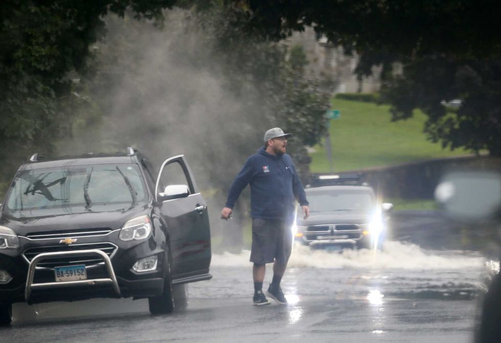 A motorist exits his car after it stalled while going through flooded out section of Southern Boulevard in Danbury, Connecticut, on August 18, 2024