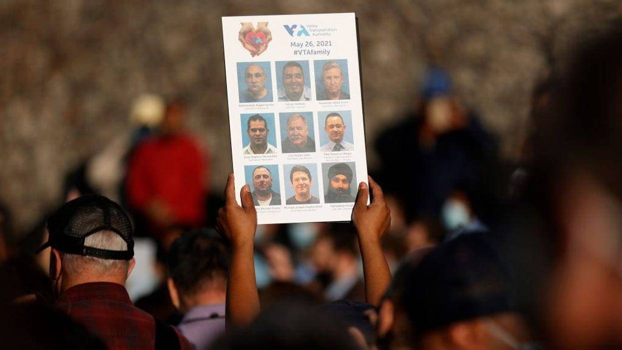 A mourner holds a sign with images of the nine Santa Clara Valley Transportation Authority (VTA) light rail yard shooting victims during a vigil at San Jose City Hall on May 27, 2021 in San Jose, California.