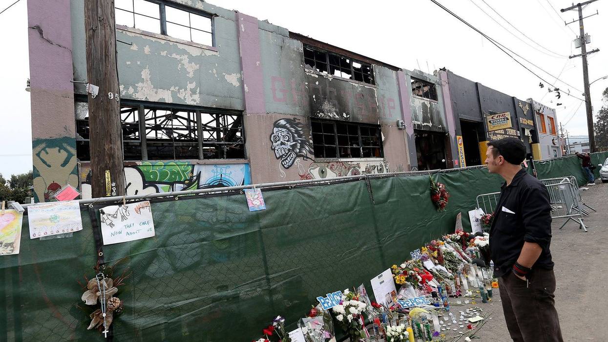 A mourner pays his respects as Investigators carry on their work at the Ghost Ship warehouse in Oakland, Calif., on December 13, 2016.