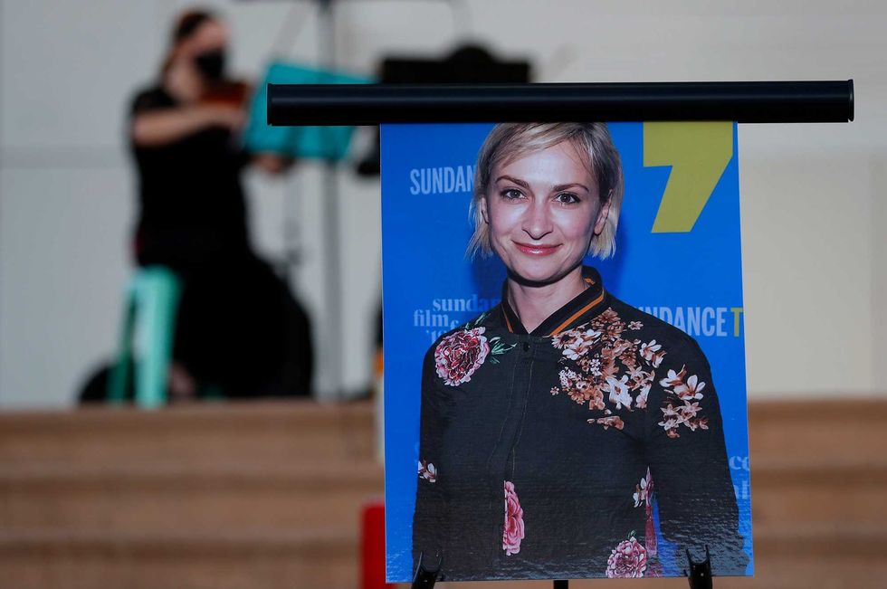 A musician plays a violin behind a photograph of cinematographer Halyna Hutchins during a vigil in her honor in Albuquerque, N.M., Saturday, Oct. 23, 2021