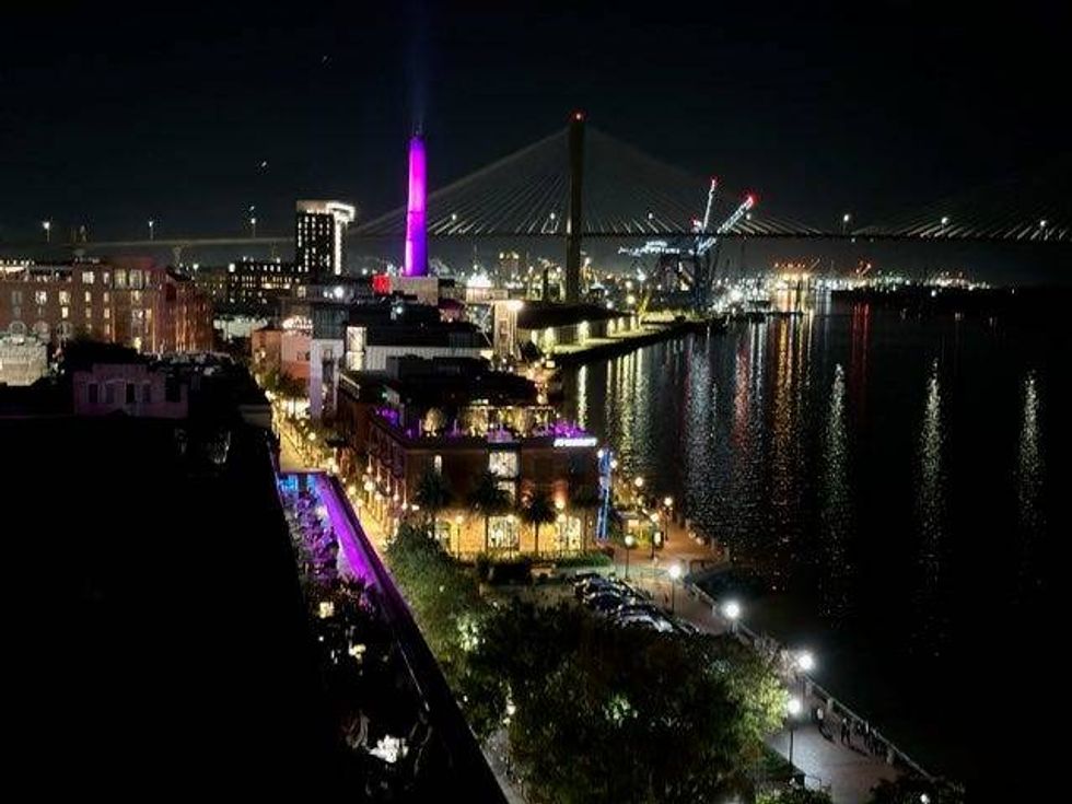 A nighttime cityscape illuminated by a soft purple glow, showcasing buildings and streets under a starry sky.