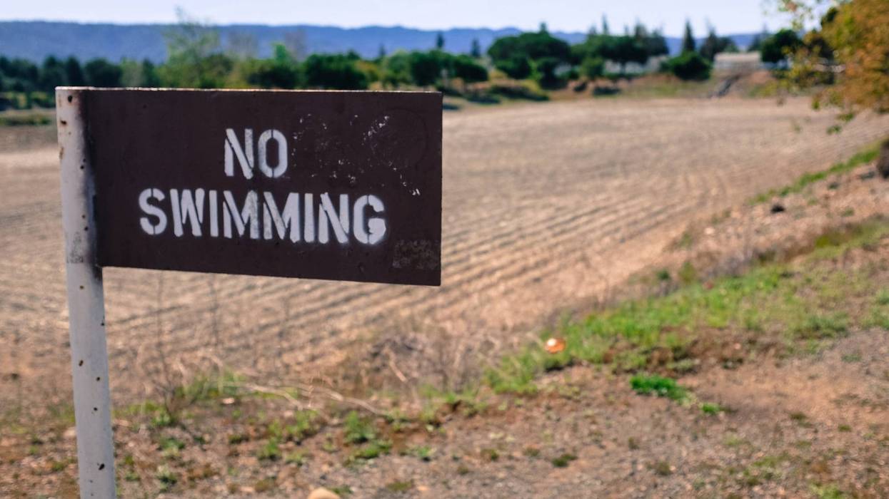 A No Swimming sign outside of a dried up water system in Santa Clara, CA.