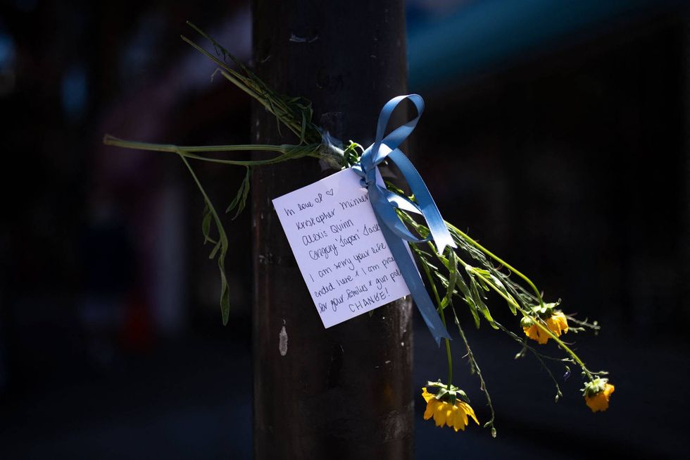 A note and flowers honoring the victims of the South Street mass shooting are taped to a traffic light post at the corner of South and Third streets in Philadelphia, Pennsylvania, on June 5, 2022.
