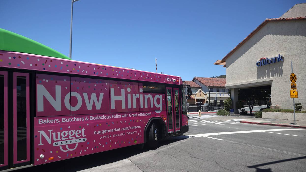 A "Now Hiring" sign for Nugget Markets is posted on the side of a Golden Gate Transit bus on July 07, 2021 in San Rafael, California.