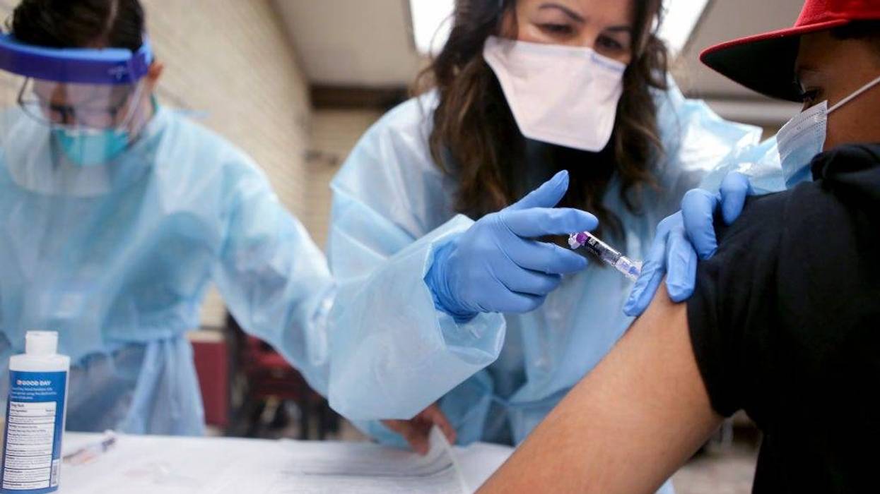 A nurse gives a flu vaccination shot to a young man at a free clinic held at a local library on October 14, 2020 in Lakewood, California.