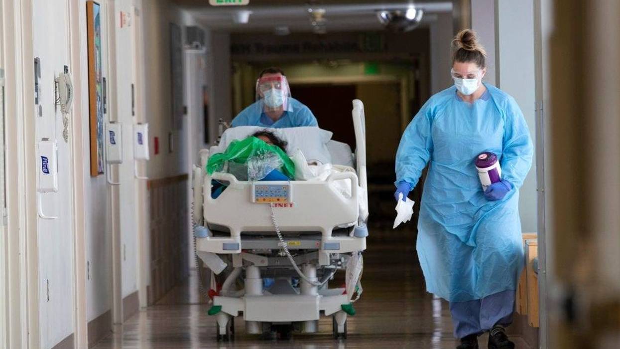 A nurse on infection control accompanies a patient being transferred from the ICU COVID unit to the acute care COVID unit at Harborview Medical Center on May 7, 2020 in Seattle, Washington.