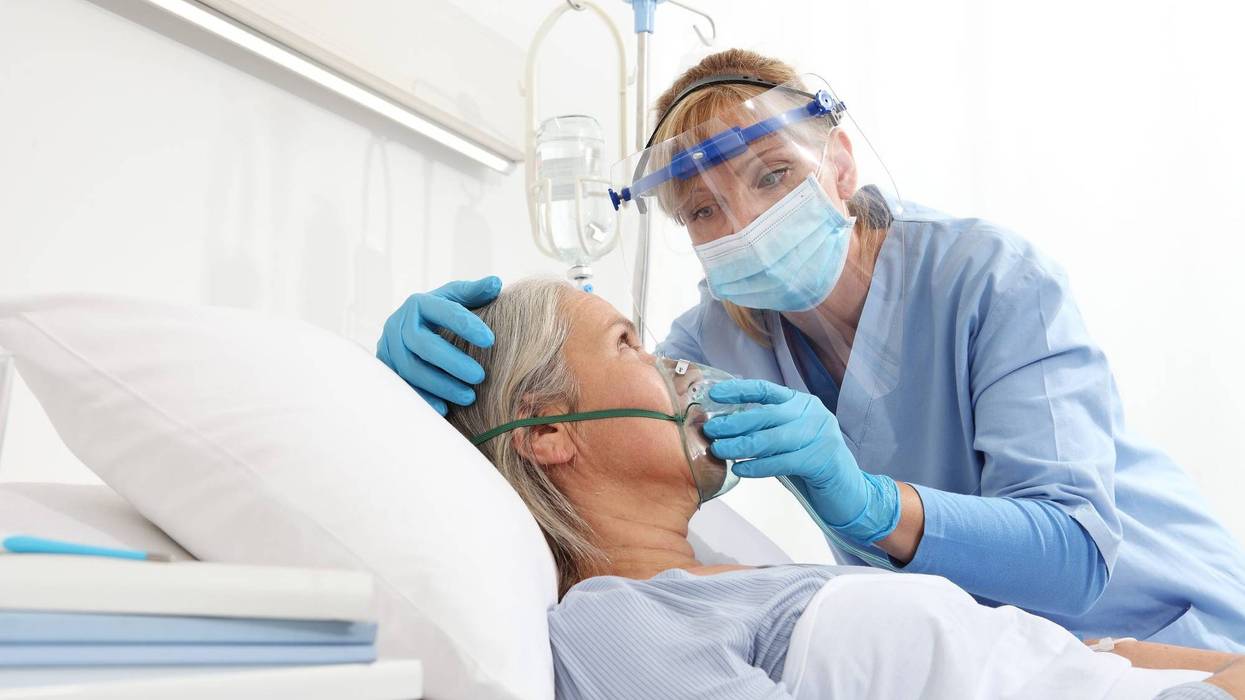 A nurse wearing a COVID-19 mask helping a hospital patient.