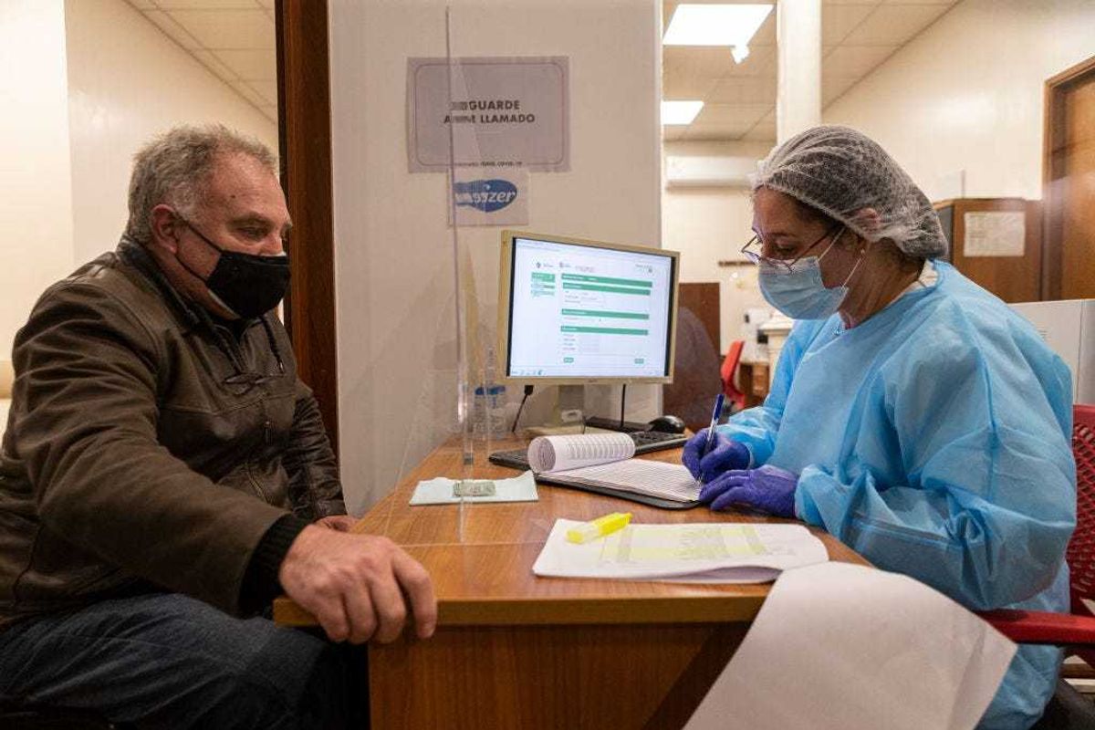 A nurse writes down the information of a man who will receive a COVID-19 vaccine.