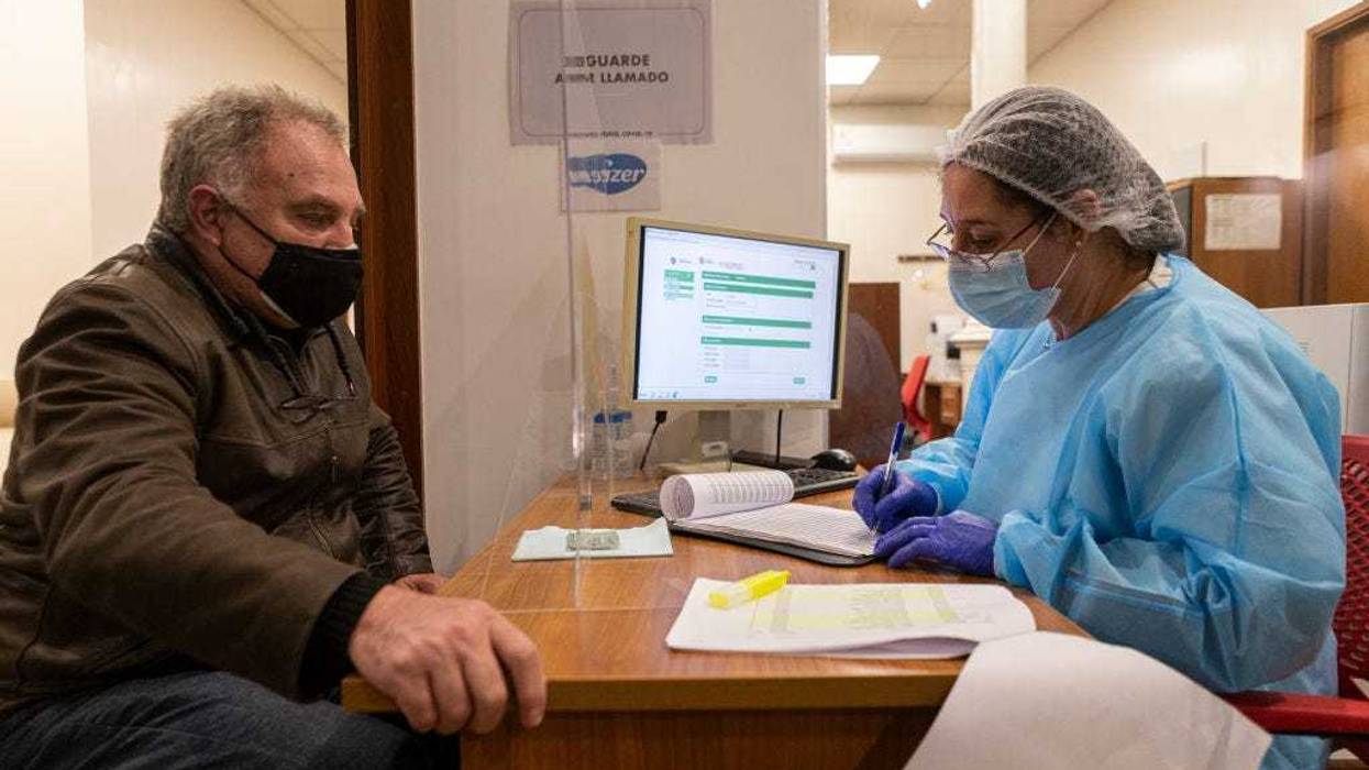 A nurse writes down the information of a man who will receive a COVID-19 vaccine.