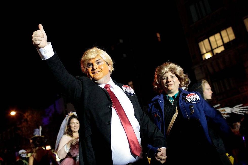 A pair dressed as Donald Trump and Hillary Clinton walk with revelers along Sixth Avenue during the 43rd annual Village Halloween Parade, October 31, 2016 in New York City.
