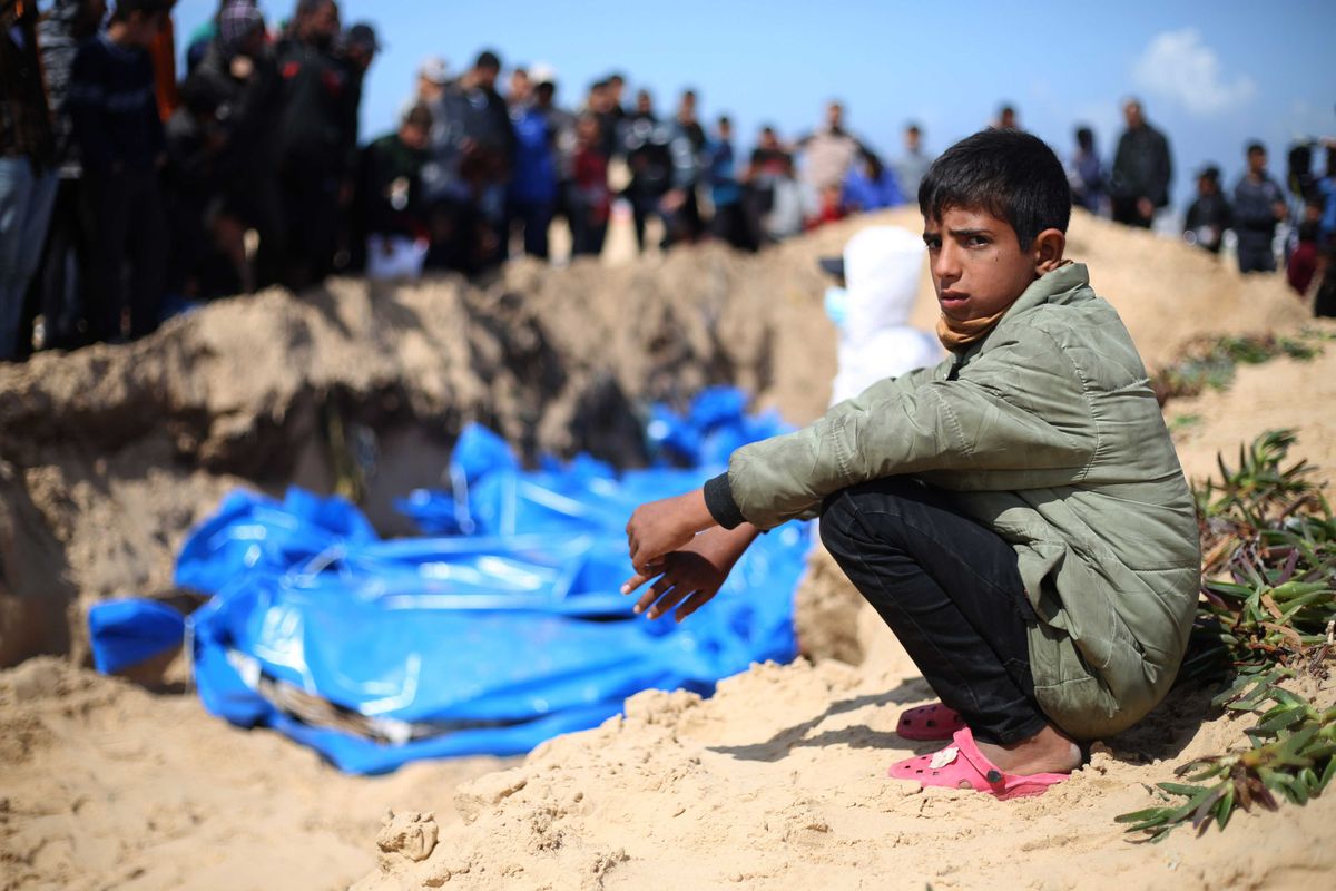 A Palestinian boy in the southern Gaza city of Rafah squats near a mass grave site for victims of Israeli military assaults in its war with Hamas