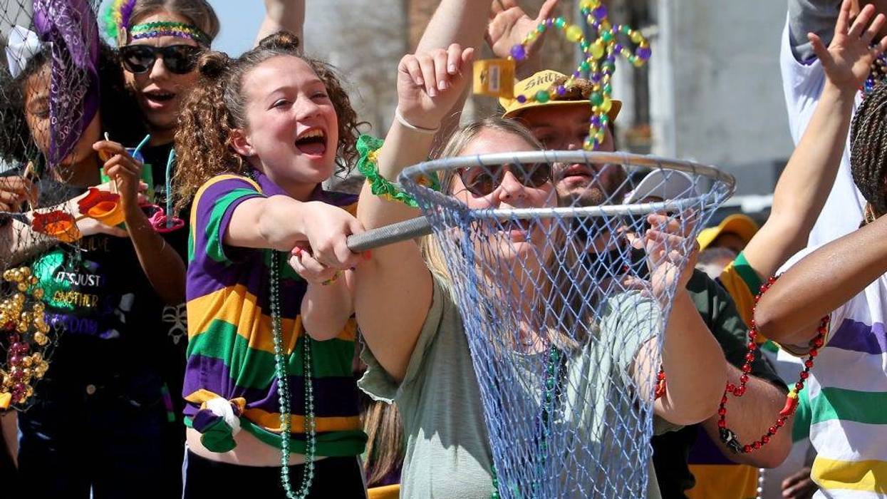 A parade-goer catches beads in a net as the 1,500 members of the Krewe of Zulu make their way down St. Charles Avenue on Mardi Gras Day