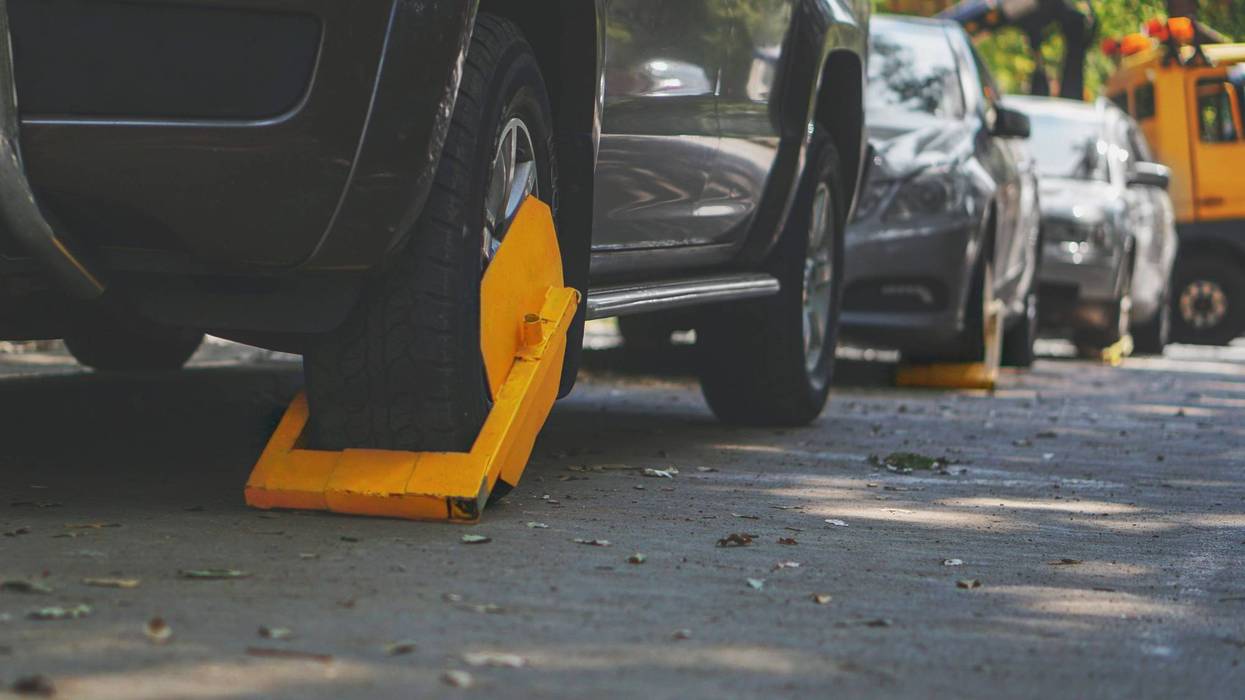 A parked car with a yellow tire lock for the illegal parking violation.