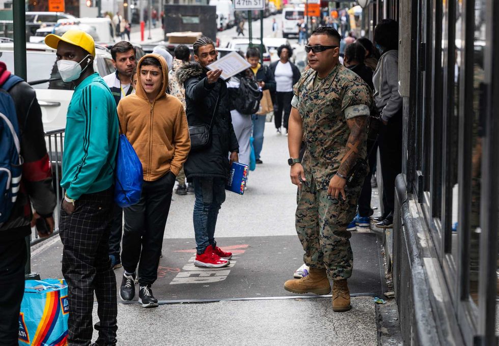 A person assists recently arrived migrants outside of the Roosevelt Hotel in Midtown Manhattan on Sept. 28, 2023