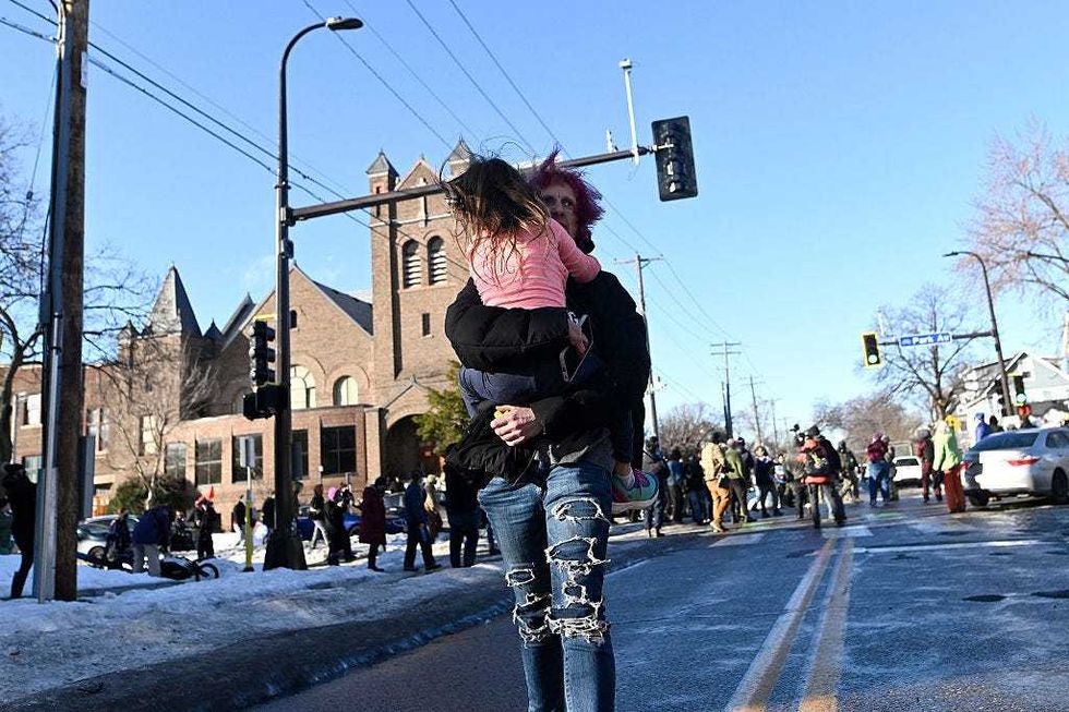 A person carries a child away from the scene where ICE agents were confronted by protestors after they arrested people from a residence on January 13, 2026 in Minneapolis, Minnesota.