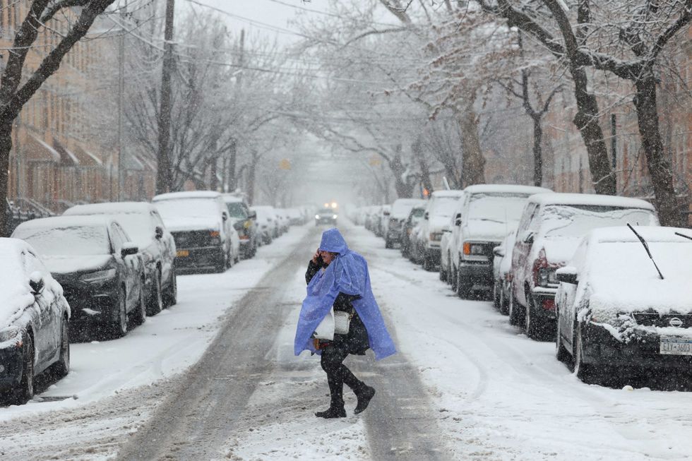 A person crosses the street as snow falls in Brooklyn on February 13, 2024